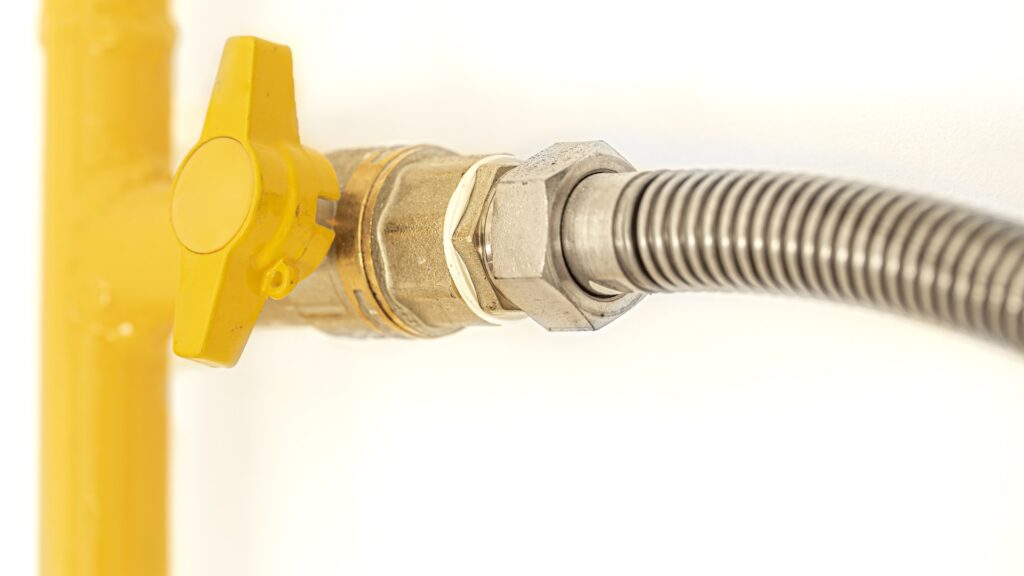 A braided stainless steel water line connected to a quarter turn shutoff valve under a kitchen sink