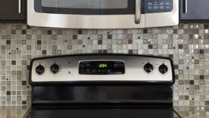 A stainless over-the-range microwave mounted above a kitchen range between wall cabinets
